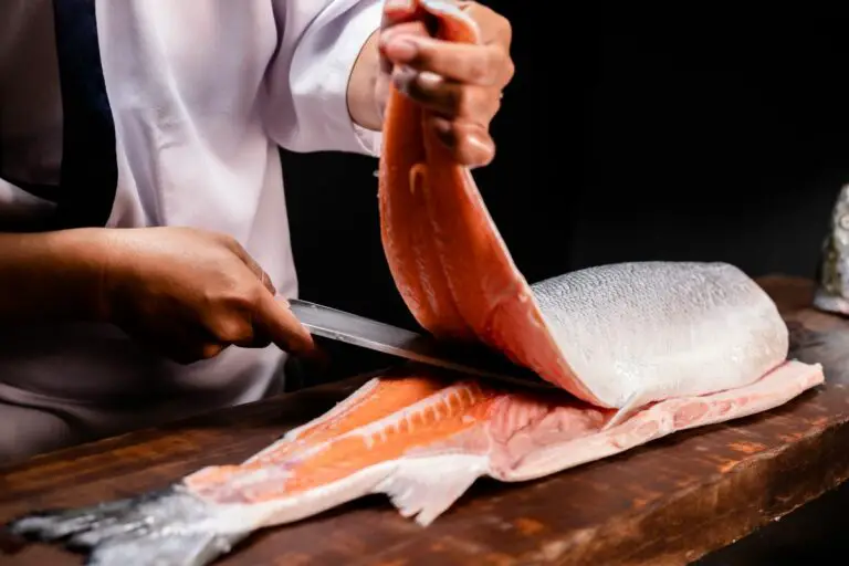 Un chef découpe un filet de saumon avec un couteau Yanagiba